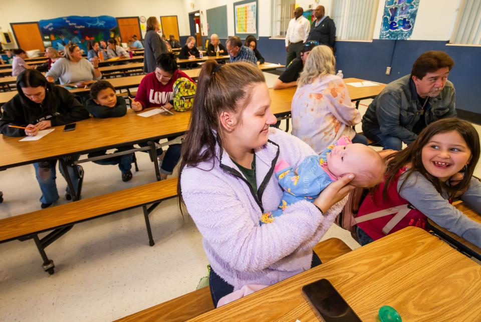 Emily Starke holds her 3-week-old daughter Lyle Gray while sitting next to her daughter Zoey Dunn, 7, right, during the year-round school meeting Thursday. “It’s different,. I think it will work for her (Zoey). It will be good for them,” Starke said.