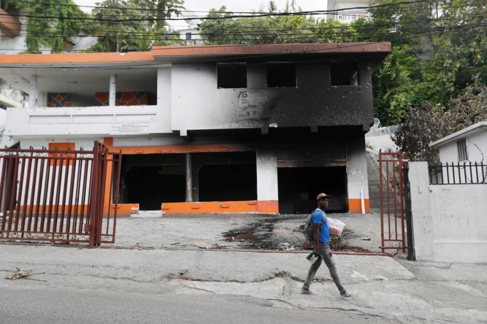 A pedestrian walks past a burned house that stands next to the residence of Haiti’s late President Jovenel Moïse near Port-au-Prince, Haiti, Thursday, July 15, 2021.