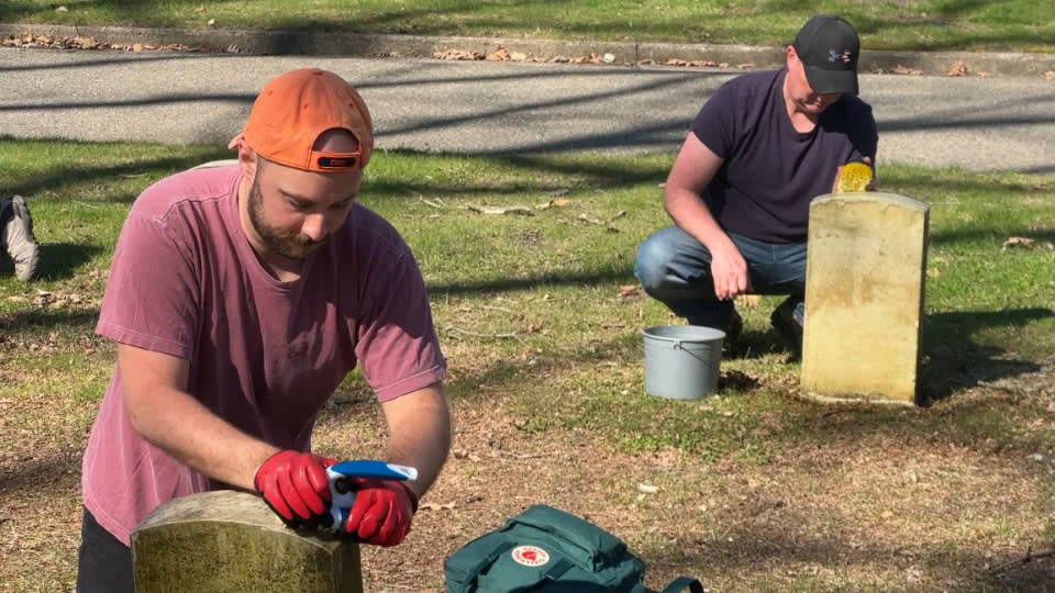 Volunteers clean graves at the Grand Rapids Veterans Home Cemetery on April 22, 2024.