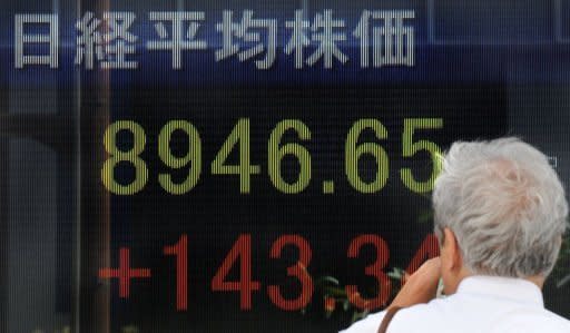 A man looks at a stock market information board in front of a securities company in Tokyo. Asian shares were mixed Tuesday as fears about the eurozone and a slowdown in China were offset by hopes the US central bank chief would this week outline steps to boost the world's biggest economy