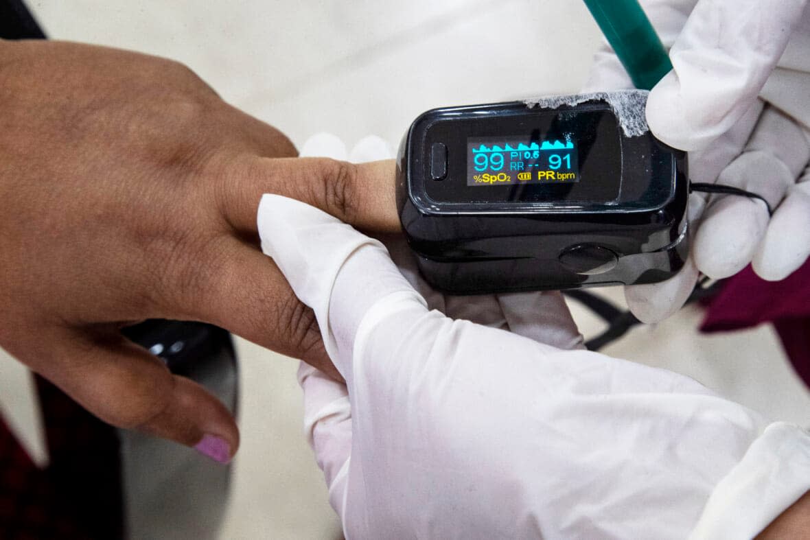 A health worker uses a pulse oximeter to check the oxygen saturation level of another after administering COVID-19 vaccine at a hospital in Gauhati, India, Jan. 21, 2021. (AP Photo/Anupam Nath, File)