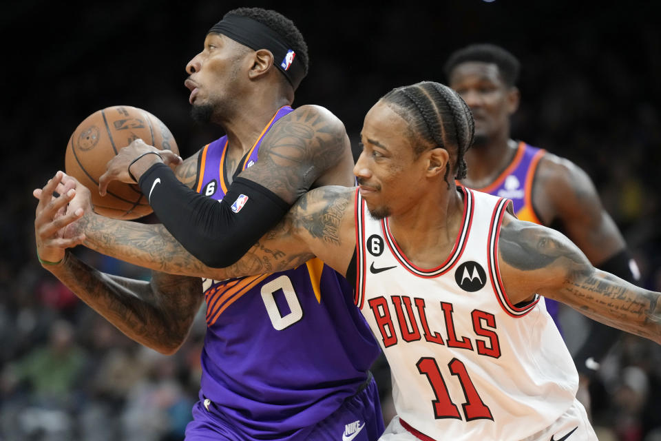 Phoenix Suns forward Torrey Craig (0) grabs a rebound away from Chicago Bulls forward DeMar DeRozan (11) during the first half of an NBA basketball game in Phoenix, Wednesday, Nov. 30, 2022. (AP Photo/Ross D. Franklin)