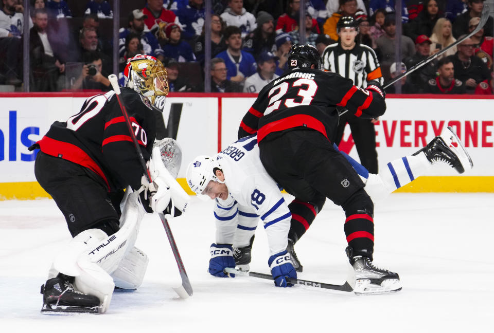 Ottawa Senators defenseman Travis Hamonic (23) upends Toronto Maple Leafs center Noah Gregor (18) in front of Ottawa Senators goaltender Joonas Korpisalo (70) during first period NHL hockey action in Ottawa, Canada, on Saturday, Feb. 10, 2024. (Sean Kilpatrick/The Canadian Press via AP)