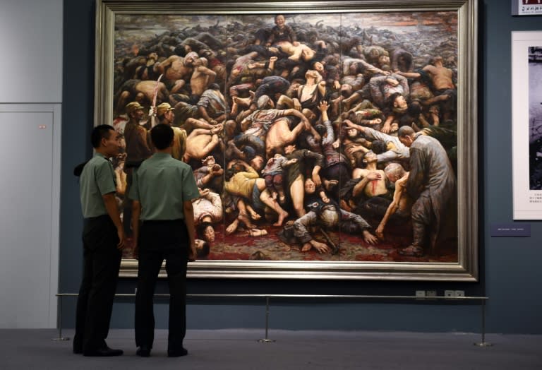 File picture shows Chinese soldiers looking at a painting depicting the Nanjing massacre, at an exhibition about World War II in Beijing