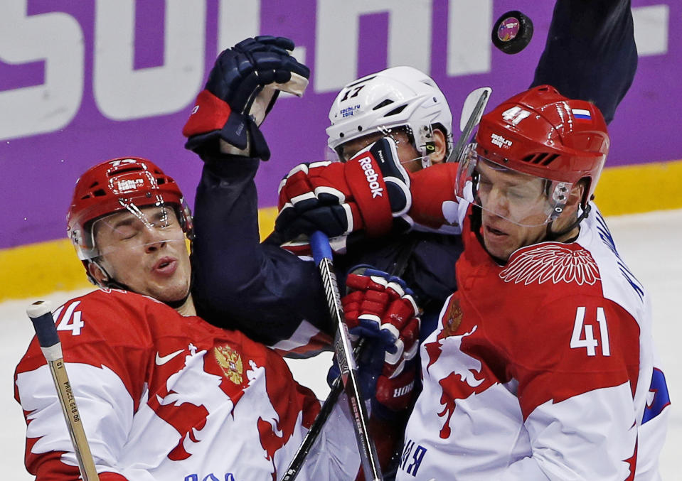 Russia defenseman Alexei Yemelin and forward Nikolai Kulyomin scramble against USA forward Ryan Kesler in the first period of a men's ice hockey game at the 2014 Winter Olympics, Saturday, Feb. 15, 2014, in Sochi, Russia. (AP Photo/Petr David Josek)