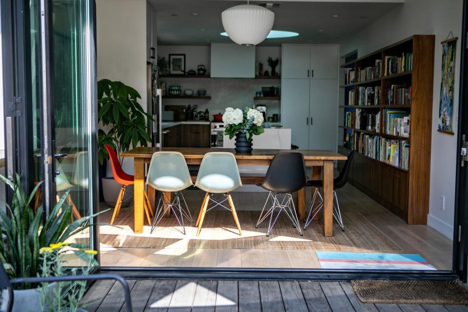 A dining table with white flowers on it as seen from a deck through open glass doors