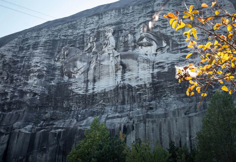 FILE- In this Oct. 5, 2020 file photo, a massive mountainside carving depicting Confederate leaders Jefferson Davis, Robert E. Lee and Stonewall Jackson is shown, in Stone Mountain, Ga. The board overseeing the mountain park has voted to relocate Confederate flags from a busy walking trail and create a museum exhibit that acknowledges the site’s connection to the Ku Klux Klan. The proposals approved Monday, May 24, 2021 were part of an effort by the Stone Mountain Memorial Association to address criticism of the park’s Confederate legacy and shore up its finances. (AP Photo/Ron Harris, File)