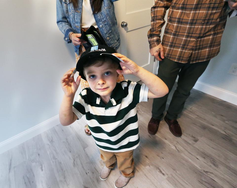 Grayson Harmon adjusts his cap while standing in his new room during the dedication of his family's new home.