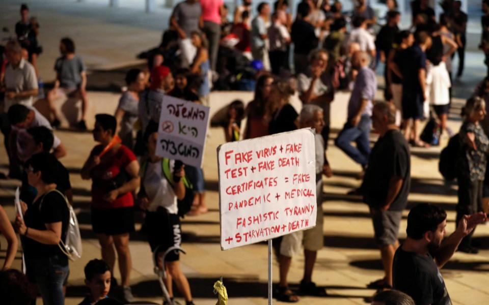 Israelis lift placards as they rally to denounce the government's renewed restrictions to combat COVID-19, in the central coastal city of Tel Aviv, on July 31, 2021. - Israel was quick to roll out its vaccination campaign and had dropped many restrictions on public gatherings in June, as new COVID-19 cases shrank from 10,000 a day to less than 100. But infections have soared in recent weeks, and masks are once again mandatory in enclosed public places, leading to the announcement on July 29 of the start of a vaccine booster campaign for over 60s, as concern mounts over the fast-spreading Delta variant of the coronavirus. - AFP