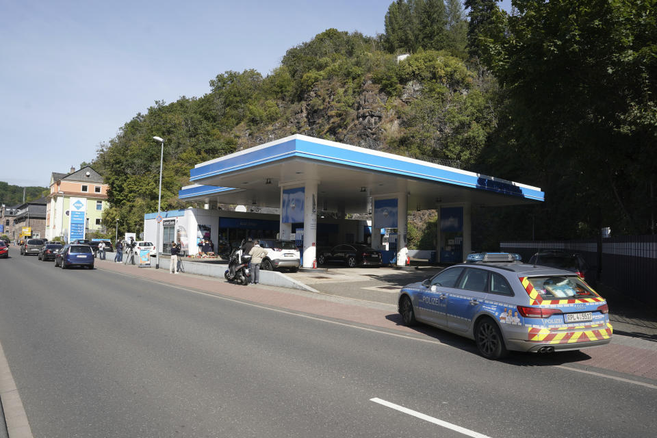 Media and a police car stand in front of a gas station in Idar-Oberstein, Germany, Tuesday, Sept. 21, 2021. Police in Germany say a 49-year-old man has been arrested on suspicion of murder in connection with the killing of the gas station worker who was shot dead Saturday at the station, following a dispute over face masks. (Thomas Frey/dpa via AP)