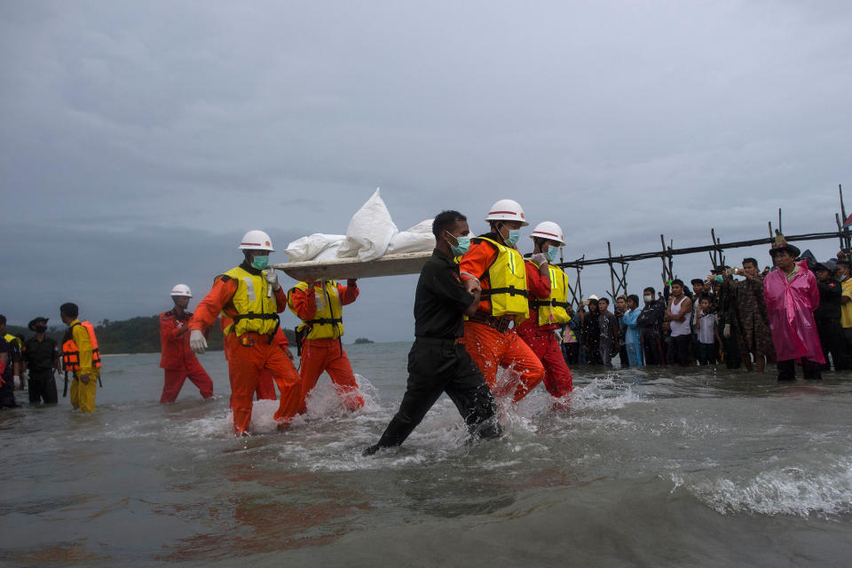 Military members and Red Cross members carry a body