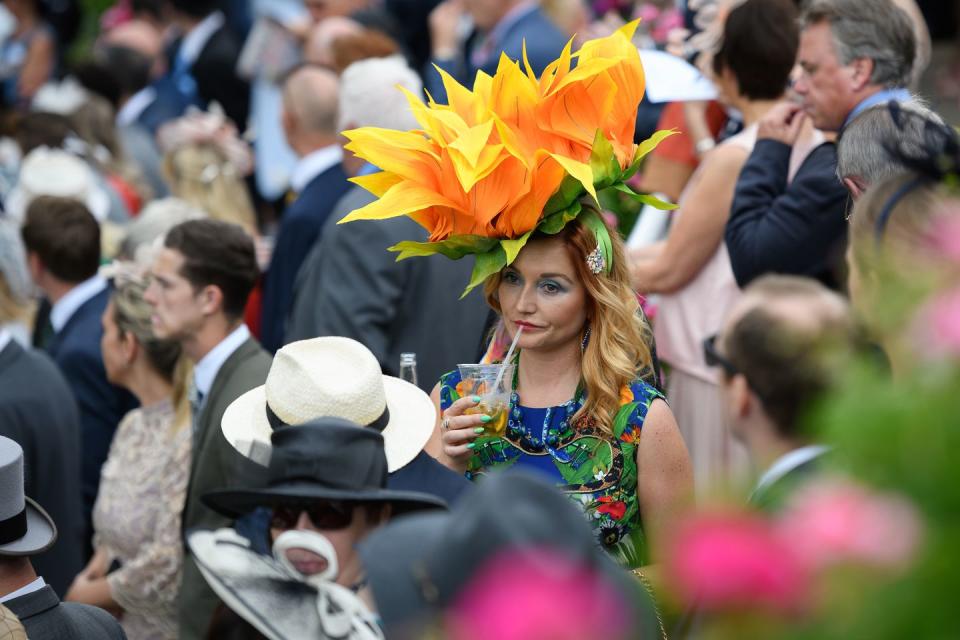 <p>A guest wearing a bright orange budding flower hat looked on from the crowd.</p>