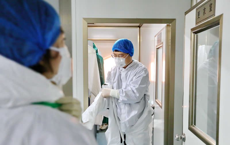 Laboratory worker puts on protective suit before examining specimens at a centre for disease control and prevention in Qinhuangdao