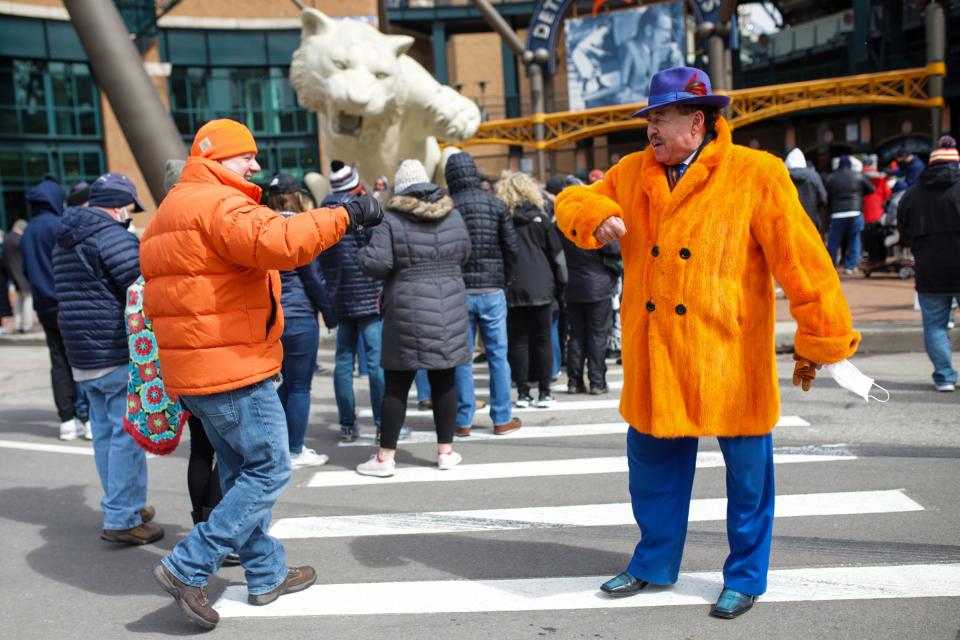 Craig Strong, a judge of the 3rd Circuit Court in Wayne County, right, bumps elbows with a fellow orange wearing fan as he waits in line outside Comerica Park on the Opening Day of the 2021 Major League Baseball season before the game between the Detroit Tigers and the Cleveland Indians on April 1, 2021, in Detroit. The afternoon brought a short flurry to the stadium with temperatures in the low 30s.  