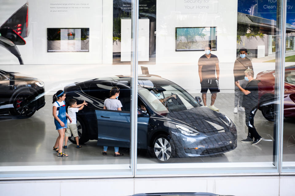 NEW YORK, NEW YORK - JULY 16: People wear face masks inside the Tesla dealership in Chelsea as New York City moves into Phase 3 of re-opening following restrictions imposed to curb the coronavirus pandemic on July 16, 2020. One of New York City's most popular attractions, the High Line re-opened with social distancing policies as part of the Phase 3 coronavirus plan. (Photo by Noam Galai/Getty Images)