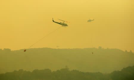 Helicopters pass each other while dropping water on the Soberanes Fire off of Rancho San Carlos Road near Carmel Valley, California, U.S. July 29, 2016. REUTERS/Michael Fiala