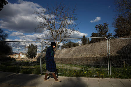 A woman walks next to a fence of the UN-controlled buffer zone in Nicosia, Cyprus February 16, 2017. REUTERS/Yiannis Kourtoglou