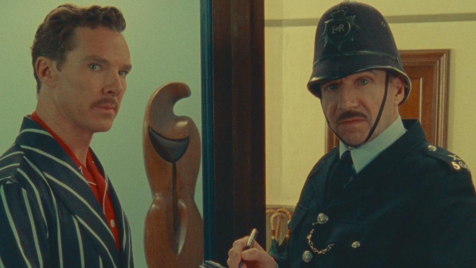 Benedict Cumberbatch in pajamas and Ralph Fiennes as an old-timey police cap with a big hat