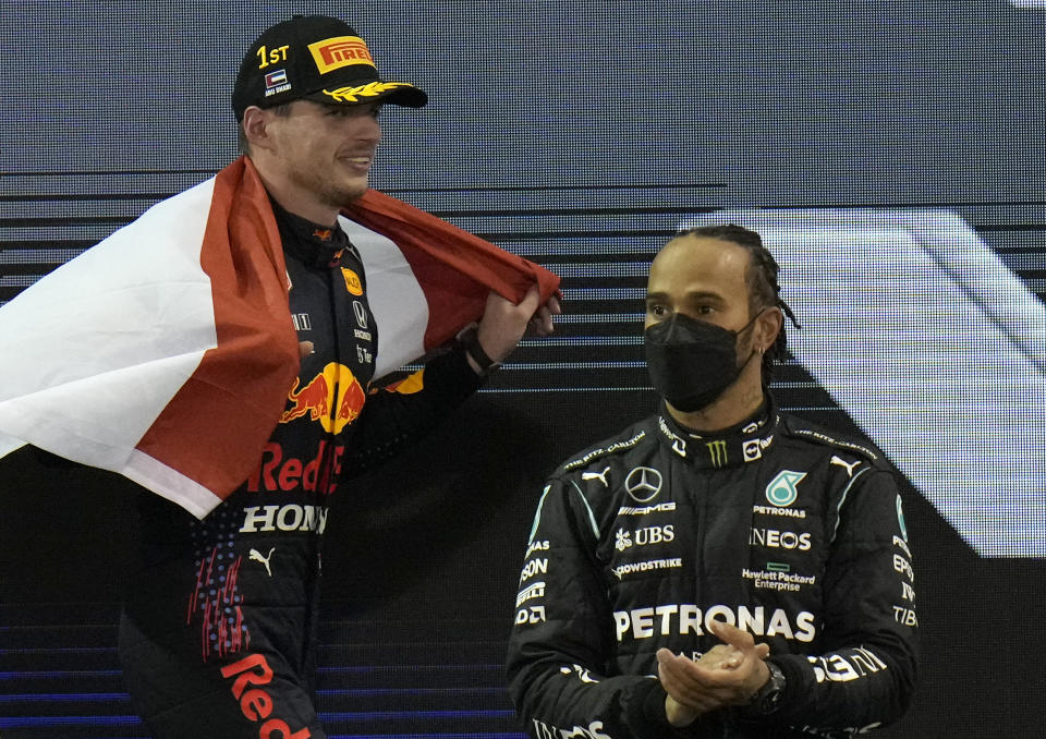 Red Bull driver Max Verstappen of the Netherlands celebrates after he became the world champion after winning the Formula One Abu Dhabi Grand Prix in Abu Dhabi, United Arab Emirates, Sunday, Dec. 12, 2021, On the right is second placed Mercedes driver Lewis Hamilton of Britain. (AP Photo/Hassan Ammar)