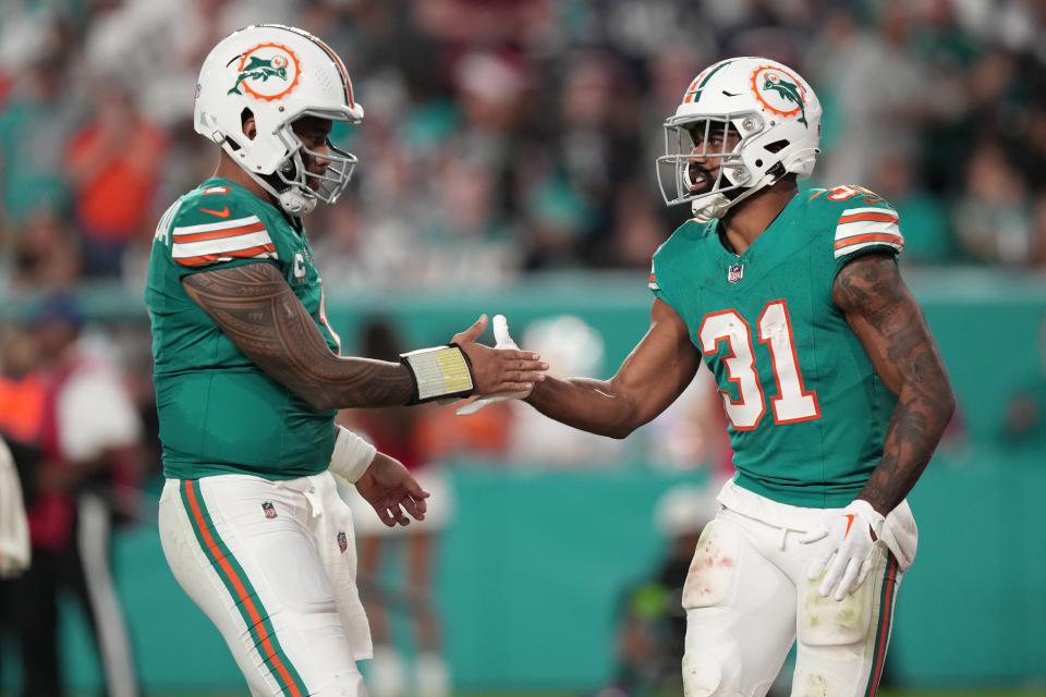 Miami Dolphins quarterback Tua Tagovailoa (1) congratulates running back Raheem Mostert (31) after scoring a touchdown against the Dallas Cowboys during the first half of an NFL game at Hard Rock Stadium in Miami Gardens, Dec. 24, 2023.