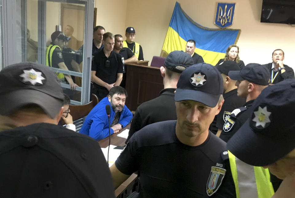 Kirill Vyshinskiy, the head of the Ukrainian office of Russia's RIA Novosti news agency in Ukraine, center, sits in a court room in Kiev, Ukraine, Friday, July 19, 2019. Ukraine's president Volodymyr Zelenskiy released a statement Friday giving details of an impending prisoner swap with Russia, saying that Kiev is willing to release a jailed Russian journalist in exchange for a Ukrainian film director. (AP Photo/Efrem Lukatsky)