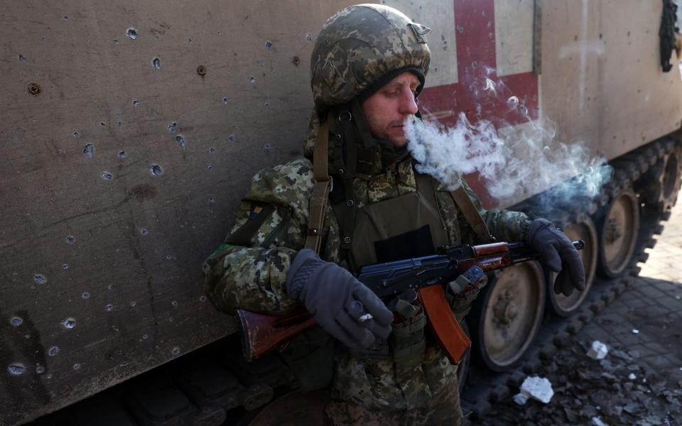 A Ukrainian serviceman smokes next to an armoured medical transport vehicle in Bakhmut - ANATOLII STEPANOV/AFP