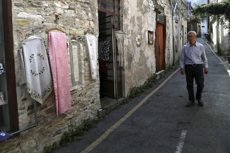 In this Tuesday Oct. 23, 2018, a man walks past shops selling the famous Lefkaritiko lace in Lefkara village, Cyprus. Legend has it that the intricate needlework used in embroidery known as ‘Lefkaritiko lace’ was of such high quality that Leonardo Da Vinci himself bought a tablecloth when he visited this mountainous village in the late 15th century and gifted it to Milan’s cathedral. (AP Photo/Petros Karadjias)