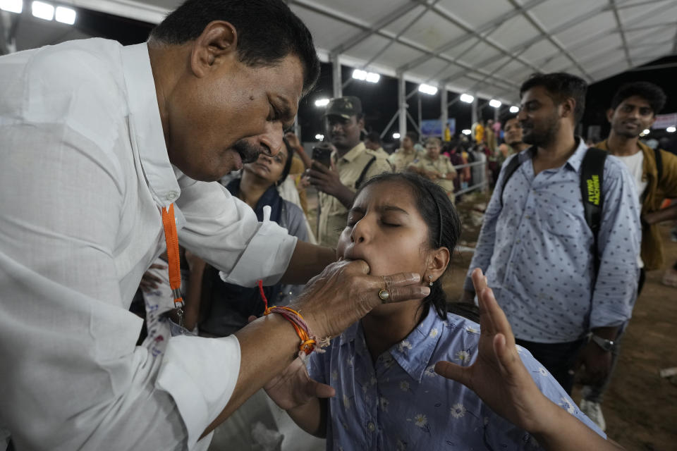 An attendant inserts a live fish stuffed with a herbal paste into the mouth of an asthmatic child, in Hyderabad, India, Saturday, June 8, 2024. Every year thousands of asthma patients arrive here to receive this fish therapy from the Bathini Goud family, a secret formula of herbs, handed down by generations only to family members. The herbs are inserted in the mouth of a live sardine, or murrel fish, and slipped into the patient's throat. (AP Photo/Mahesh Kumar A.)