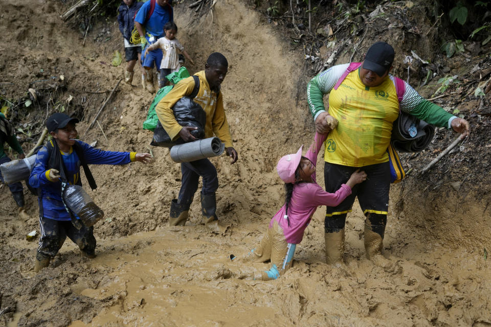 FILE - An Ecuadorian father helps his daughter traverse the mud in the Darien Gap, as they walk from Colombia into Panama, hoping to eventually reach the U.S., Oct. 15, 2022. (AP Photo/Fernando Vergara, File)