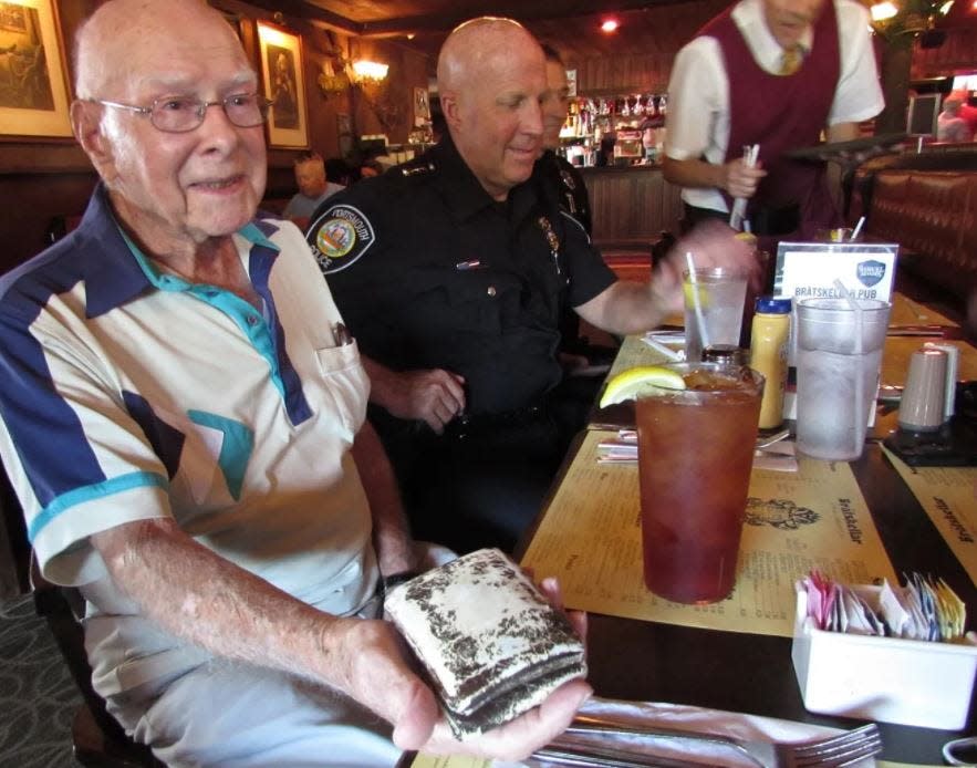 World War II veteran Ray Goulet pulls out the wallet he carried on D-Day and the rest of his life during a lunch out with Portsmouth police officers and then-Chief Robert Merner Sept. 27, 2017 at the Dinnerhorn Bratskeller restaurant.