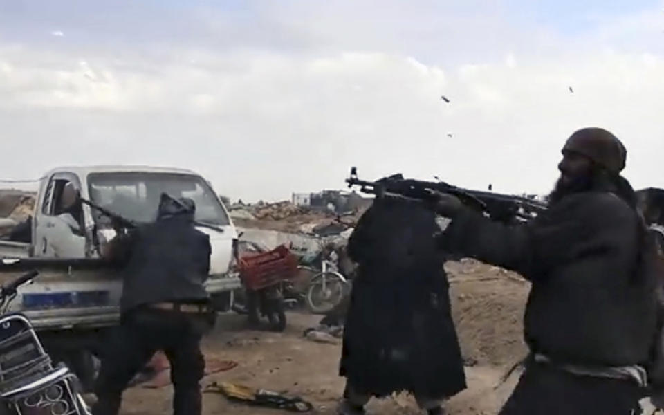 This frame grab from video posted online Monday, March 18, 2019, by the Aamaq News Agency, a media arm of the Islamic State group, shows Islamic State fighters firing their weapons during clashes with the U.S.-backed Syrian Democratic Forces (SDF) fighters, in Baghouz, the Islamic State group's last pocket of territory in Syria. U.S.-backed Syrian forces fighting the Islamic State group announced Tuesday they have taken control over an encampment in an eastern Syrian village where IS militants have been besieged for months, refusing to surrender. (Aamaq News Agency via AP)