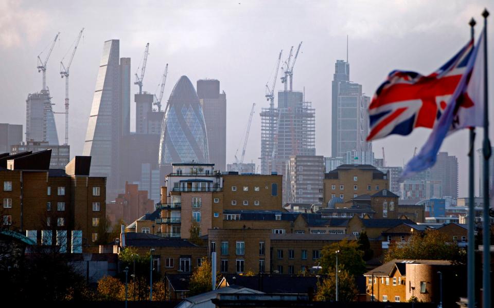 A Union flag flies from a pole as construction cranes stand near skyscrapers in the City of London, including the Heron Tower, Tower 42, 30 St Mary Axe commonly called the "Gherkin", the Leadenhall Building, commonly called the "Cheesegrater", as they are pictured beyond blocks of residential flats and apartment blocks, from east London on October 21, 2017. / AFP PHOTO / Tolga AKMEN (Photo credit should read TOLGA AKMEN/AFP via Getty Images) - TOLGA AKMEN/AFP via Getty Images