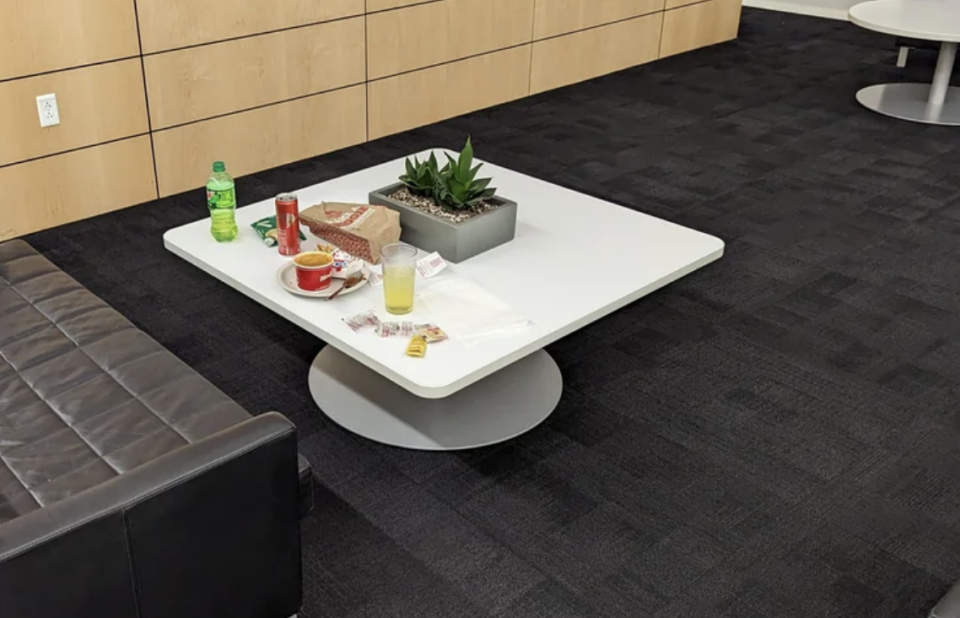 Table in a lounge area with drinks, food items, a plant, and no persons visible