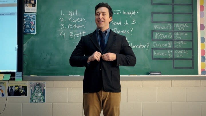 A teacher stands in front of the class buttoning his blazer in English Teacher.