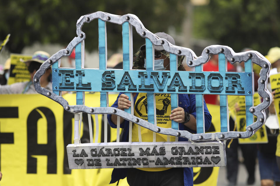 A protester holds a sign that reads in Spanish "El Salvador, the biggest jail in Latin America" during an anti-government march on International Labor Day in San Salvador, El Salvador, Monday, May 1, 2023. (AP Photo/Salvador Melendez)