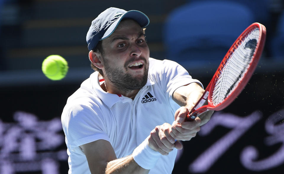 Russia's Aslan Karatsev hits a backhand to Canada's Felix Auger-Aliassime during their fourth round match at the Australian Open tennis championships in Melbourne, Australia, Sunday, Feb. 14, 2021. The Australian Open continues but without crowds after the Victoria state government imposed a five-day lockdown in response to a COVID-19 outbreak at a quarantine hotel. (AP Photo/Andy Brownbill)