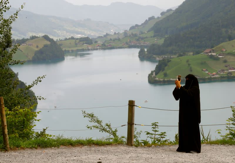 FILE PHOTO: A woman takes a picture from a lookout at Bruenigpass mountain pass road