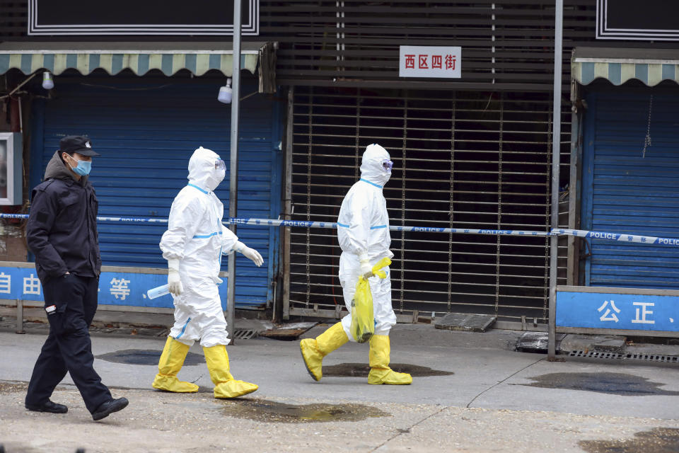 FILE - In this Jan. 27, 2020, file photo, workers in protective gear carry a bag containing a giant salamander that was reported to have escaped from the Huanan Seafood Market in Wuhan in central China's Hubei Province. A 10-member team of international researchers from the World Health Organization hopes to find clues as to the origin of the coronavirus pandemic in the central Chinese city of Wuhan where the virus was first detected in late 2019. (Chinatopix via AP, File)