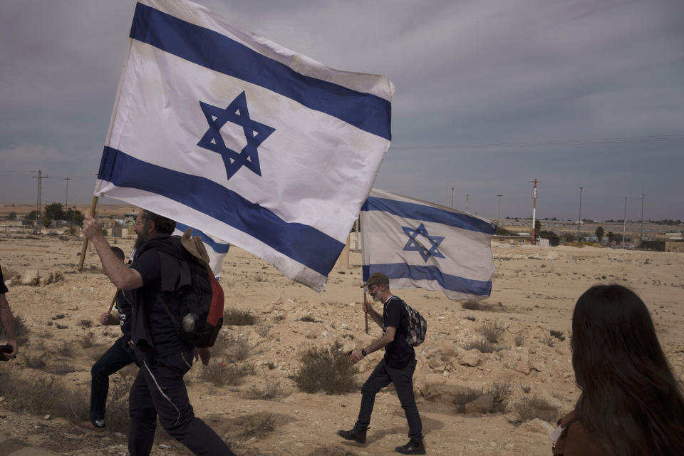 People walk toward the Nitzana border crossing with Egypt in southern, Israel, Monday, Feb. 12, 2024, protesting against the humanitarian aid to enter Gaza until all the hostages are released. (AP Photo/Leo Correa)