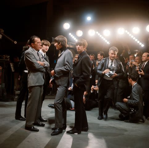 <p>Bettmann Archive/Getty</p> The Beatles converse with TV host Ed Sullivan onstage at CBS Studio 50, February 1964