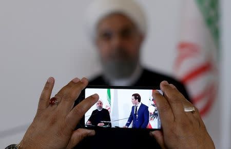 Iran's President Hassan Rouhani and Austria's Chancellor Sebastian Kurz are seen on the mobile phone screen as they attend a news conference at the Chancellery in Vienna, Austria July 4, 2018. REUTERS/Lisi Niesner