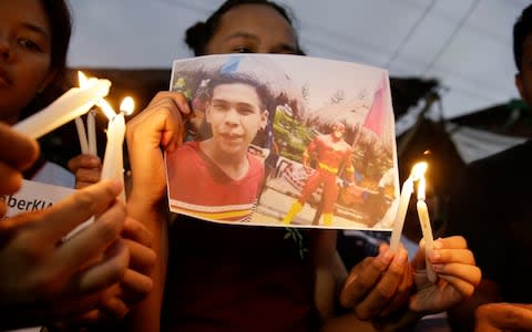 Activists light candles in front of the picture of 17-year-old student Kian Loyd delos Santos in Manila - Credit: AP Photo/Aaron Favila