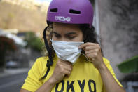 La ciclista medalista olímpica Stefany Hernández se pone su máscara antes de salir a entrenar en las calles de Caracas, Venezuela. A pesar del confinamiento por la pandemia de COVID-19, la ciclista de BMX entrena tres días a la semana y busca calificar a los Juegos Olímpicos de Tokio en el 2020. (AP Photo/Matias Delacroix)