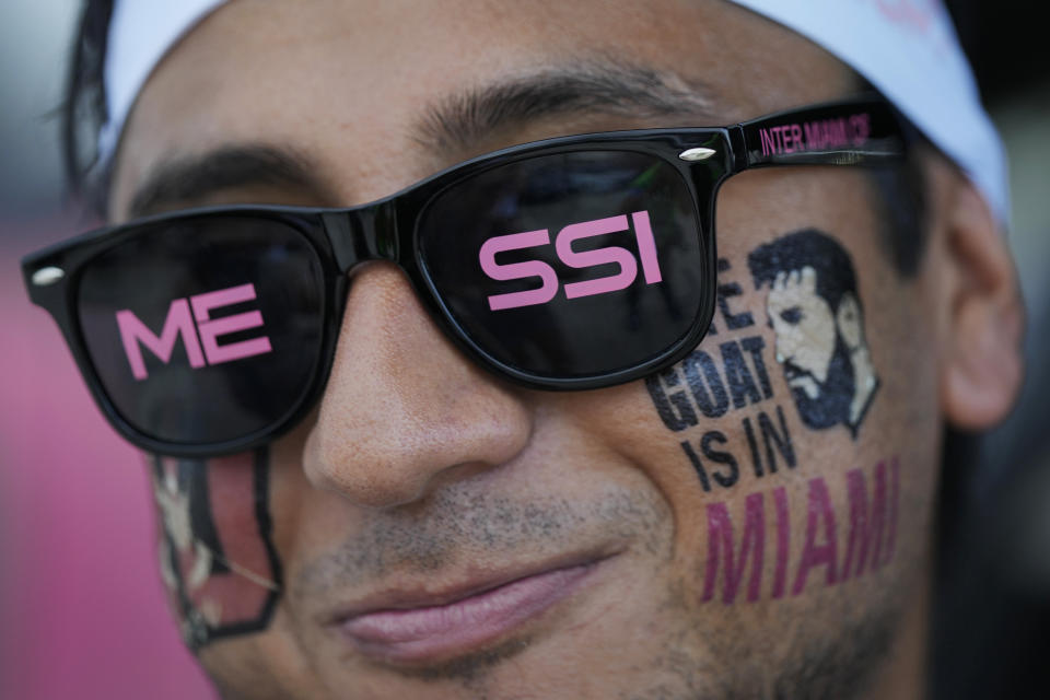 FILE - A man wears temporary tattoos supporting Lionel Messi as fans wait for gates to open for Inter Miami's Leagues Cup soccer match against Orlando City, Wednesday, Aug. 2, 2023, in Fort Lauderdale, Fla. Since Messi arrived in the United States, both the league and his team, Inter Miami, have enjoyed a bump with jerseys flying off the shelves, ticket prices reaching unheard-of levels and sponsors jumping on board. (AP Photo/Rebecca Blackwell, File)