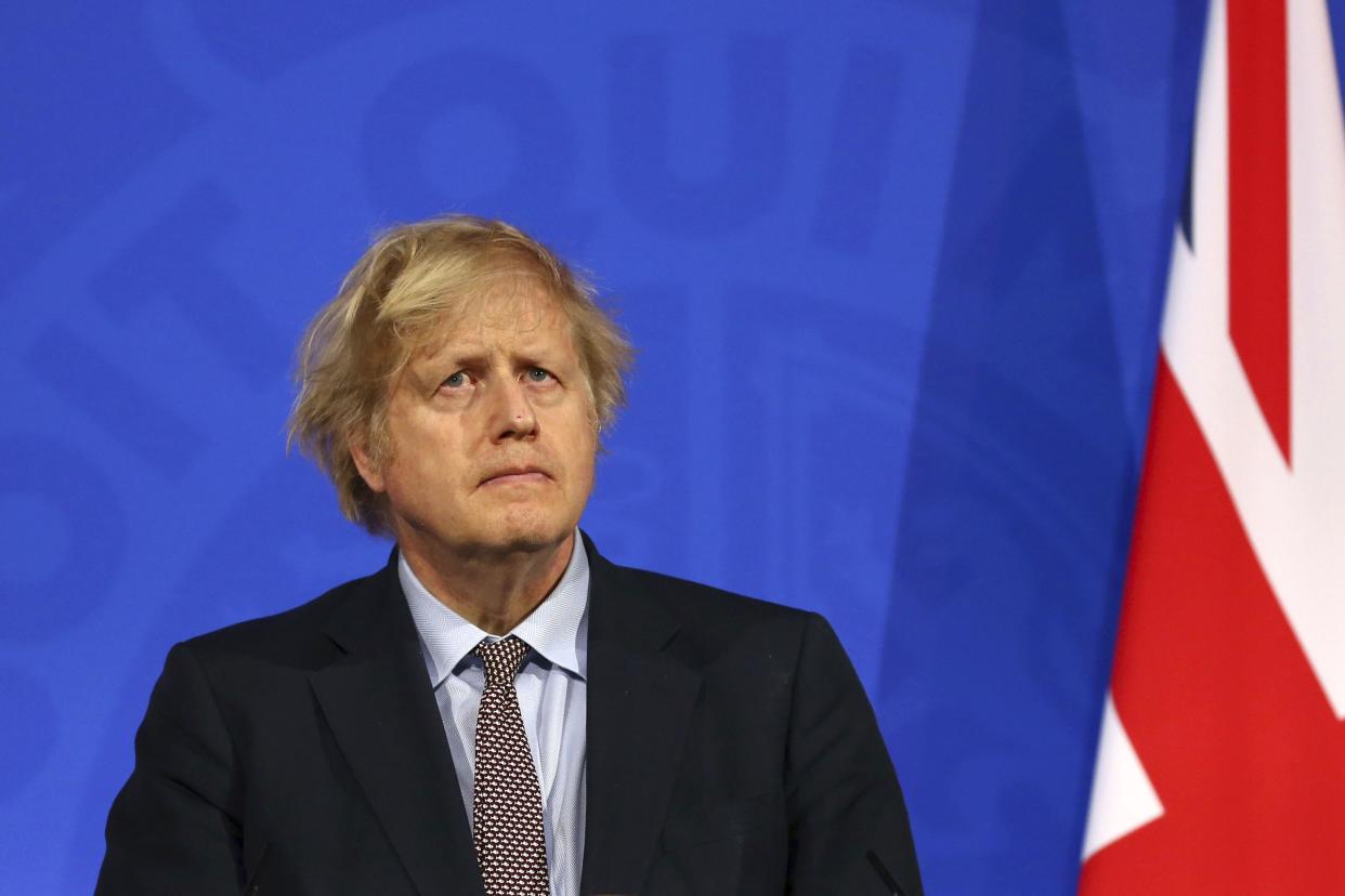 Boris Johnson stands in front of a British flag.