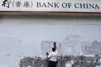 A worker cleans graffiti from a Bank of China branch that had been previously boarded up to prevent damages during protests in Causeway Bay district, in Hong Kong