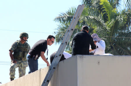 A soldier stands guard as forensic technicians work at a crime scene where the body of a man, who witnesses said was tossed from a plane, landed on a hospital roof in Culiacan, in Mexico's northern Sinaloa state April 12, 2017. REUTERS/Jesus Bustamante