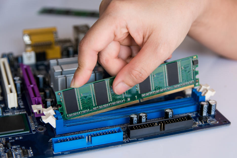 Technician installing RAM stick (random access memory) to socket on motherboard