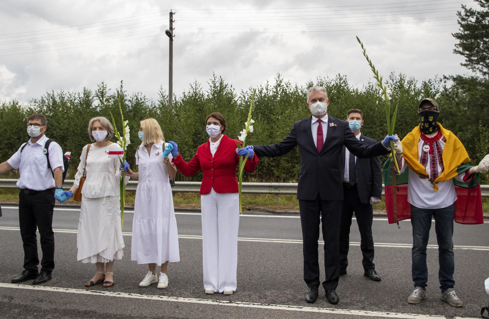 Lithuania's President Gitanas Nauseda, right, and his wife Diana Nausediene, second from right, and other supporters of Belarus opposition participate in a "Freedom Way", a human chain of about 50,000 strong from Vilnius to the Belarusian border, during a protest near Medininkai, Lithuanian-Belarusian border crossing east of Vilnius, Lithuania, Sunday, Aug. 23, 2020. In Aug. 23, 1989, around 2 million Lithuanians, Latvians, and Estonians joined forces in a living 600 km (375 mile) long human chain Baltic Way, thus demonstrating their desire to be free. Now, Lithuania is expressing solidarity with the people of Belarus, who are fighting for freedom today. (AP Photo/Mindaugas Kulbis)