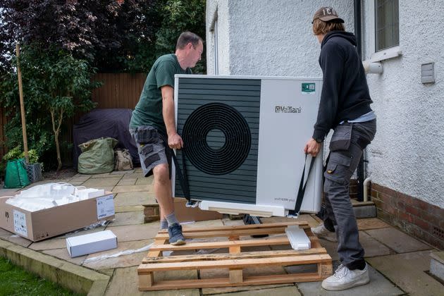 Workers install a Vaillant Arotherm plus 7-kW air source heat pump unit into a 1930s-built house in Folkestone, United Kingdom, which has offered big incentives for heat pump adoption. (Photo: Andrew Aitchison via Getty Images)